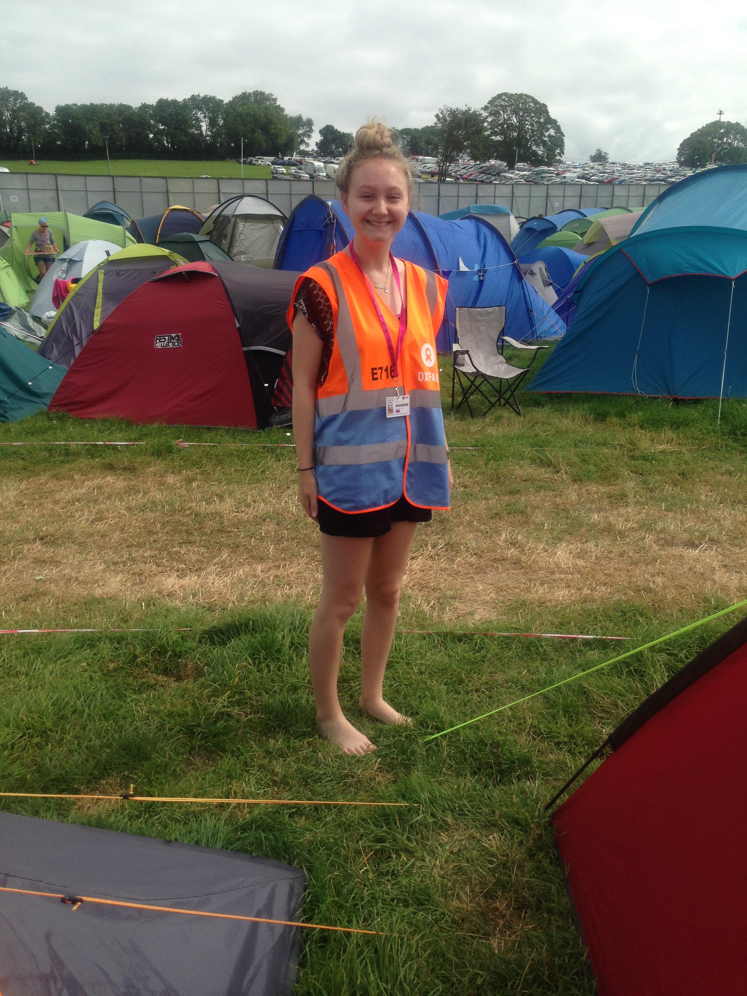 Anna stood amongst tents, wearing a high-visibility jacket at Glastonbury.